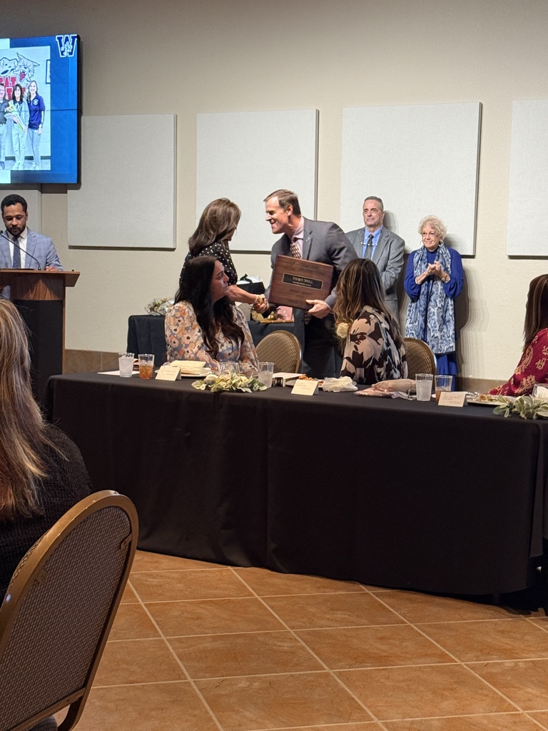 People sit at a table. One person hands a woman a plaque. They stand by the table.