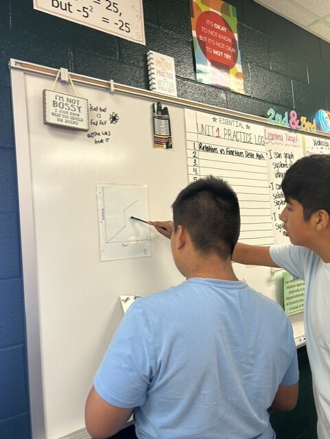 The picture shows 2 students analyzing a time and distance graph.