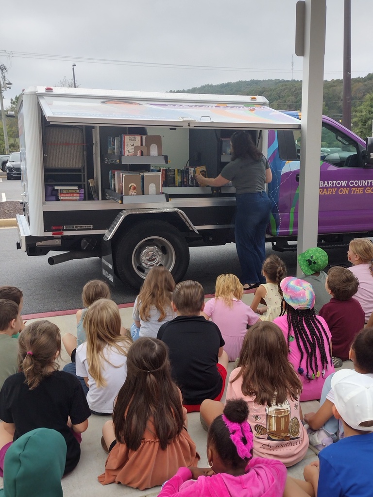 students at a bookmobile sitting on the ground