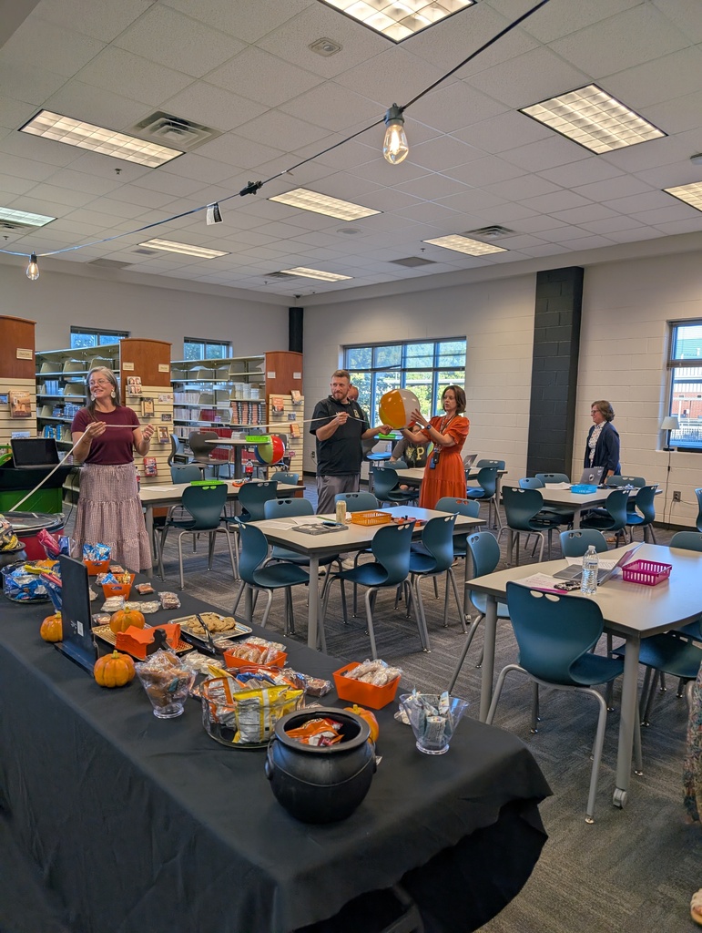Teachers stand with a tape measure and a beach ball as they determine at what point the "moon" (a marble) blocks out the "sun" (a beach ball).