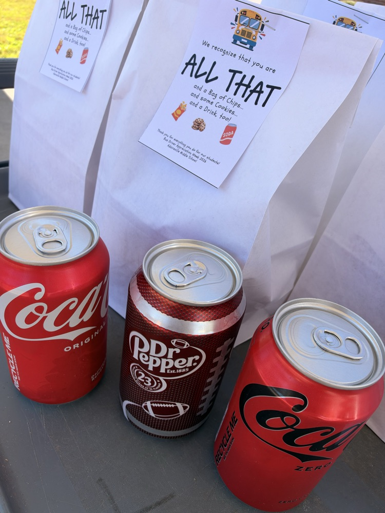 Three cans of soft drinks, two Coca-Cola and one Dr. Pepper, in front of a white bag.