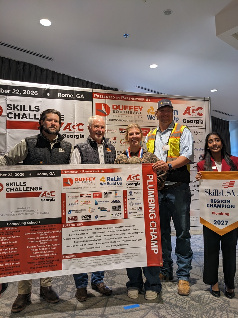 Five people stand with a large certificate. The woman on the right holds a sign reading SkillsUSA Region Champion 2027.