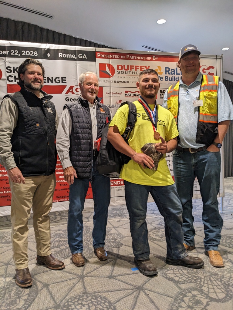 Five men stand next to each other in front of a banner with words and logos.