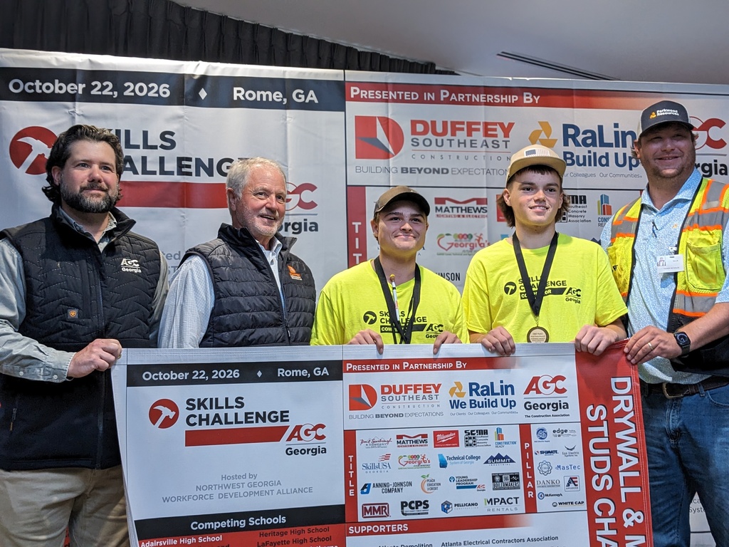 Five men pose with a banner. The man in the middle holds a large sign with the text "Drywall & Ceiling".