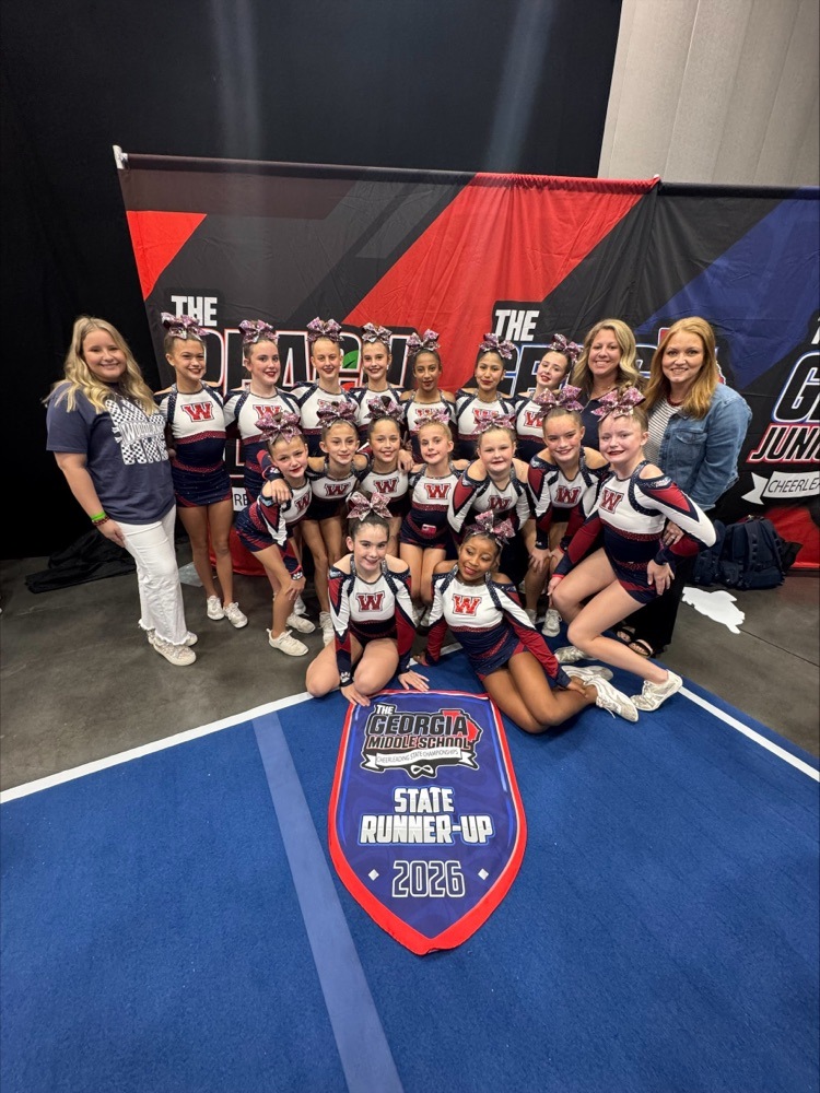 Team wearing cheerleading uniforms, some sitting and others standing, posing for a photo with a Georgia State Runner-Up 2026 sign on a blue mat.