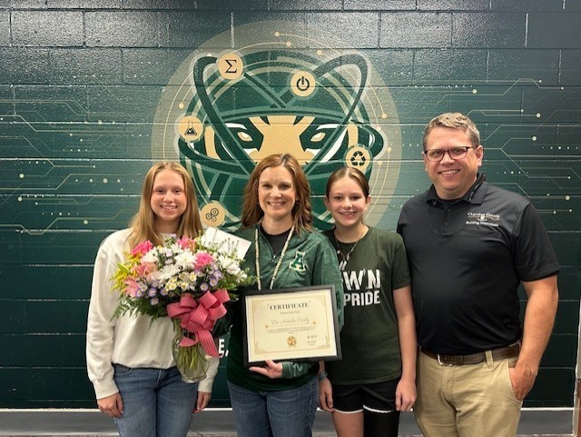 AHS Teacher of the year stands with her family with  flowers and award