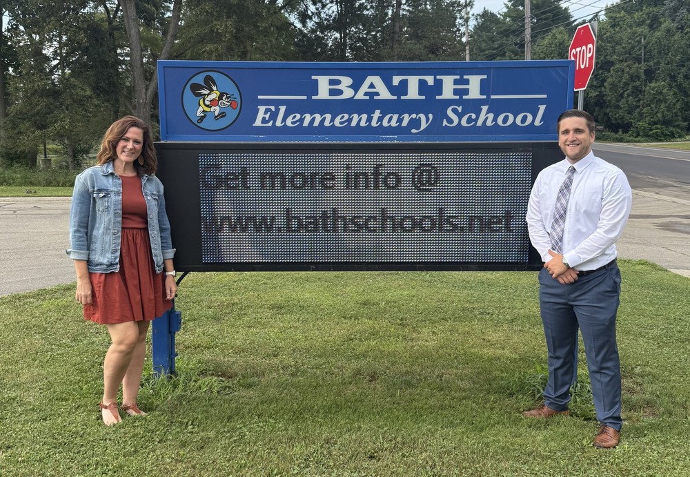Mrs. Sykes and Mr. Greenawalt standing next to sign