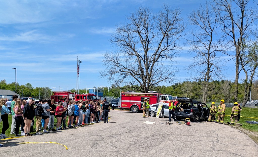 First responders demonstrating a mock car accident  while students watch