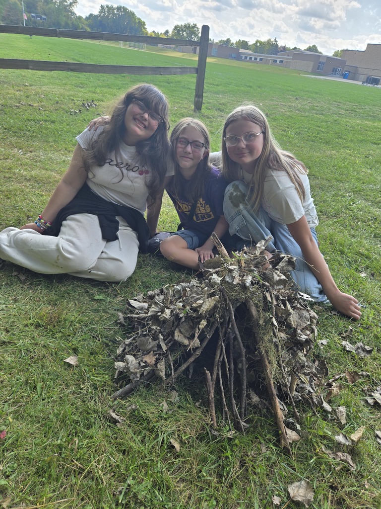 3 girls sitting on grass next to project