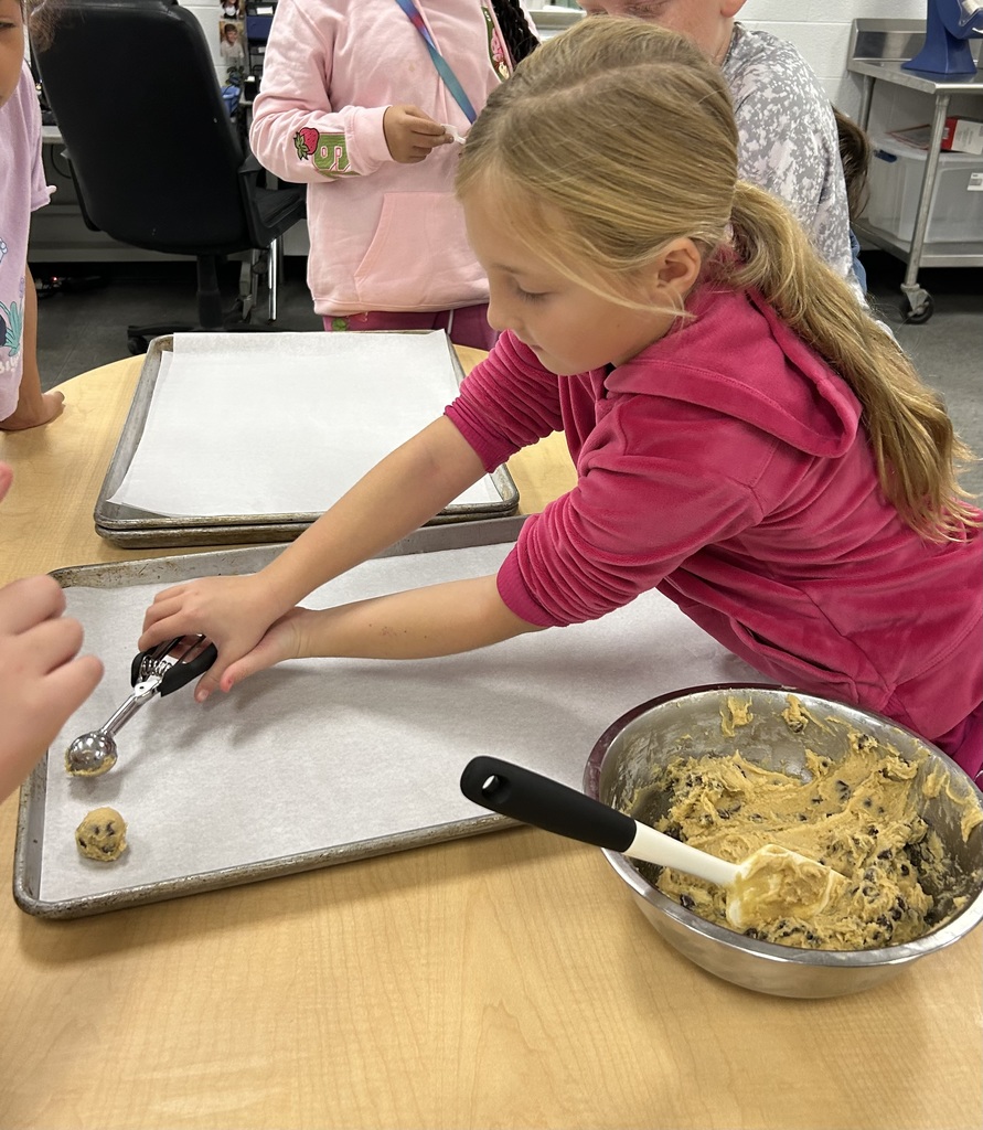 Girl scooping cookie down on to baking pan