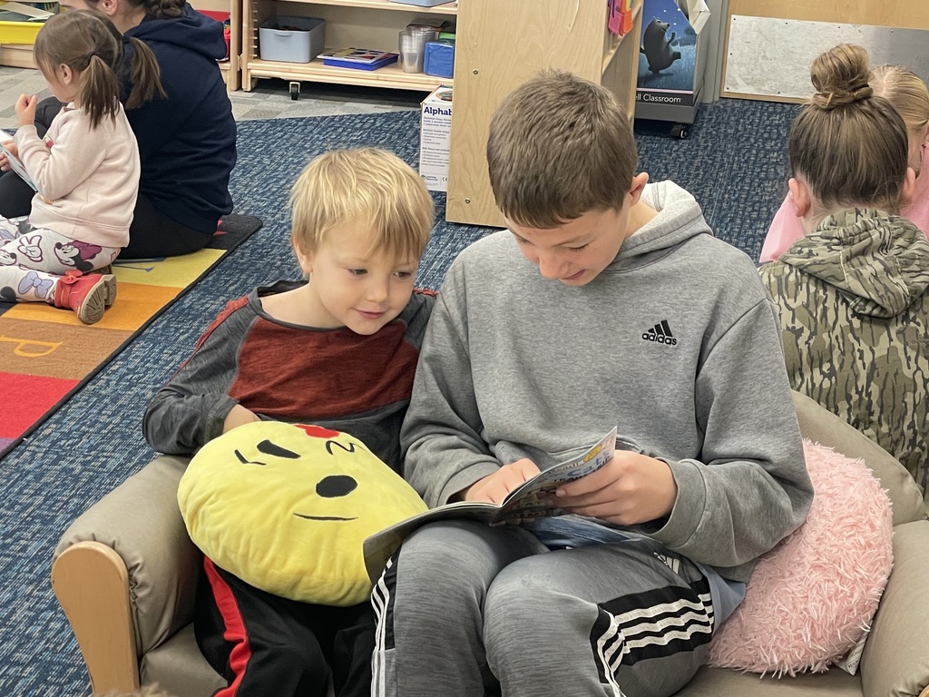 A middle school student reading with  an elementary student