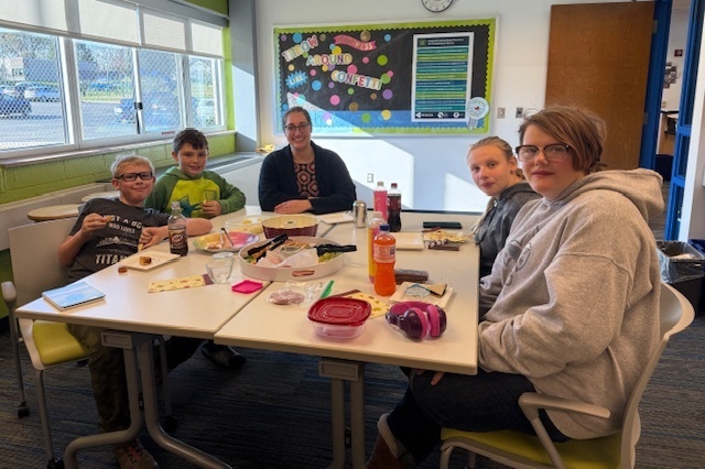 Four students and one staff member sitting around a lunch table.