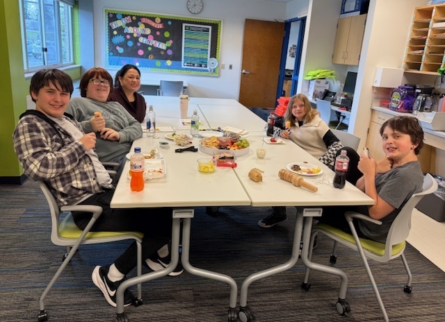 Four students and one staff member sitting around a lunch table.