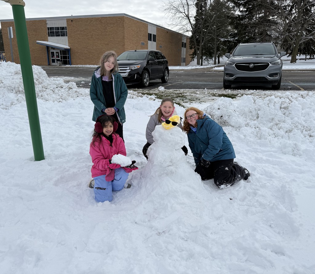 Students gathered around a snowman. 