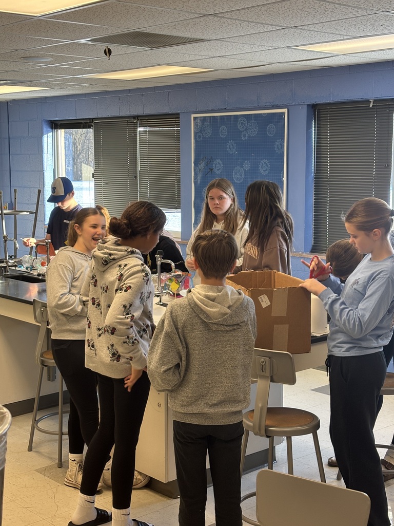 Students standing around a table working on a science project.