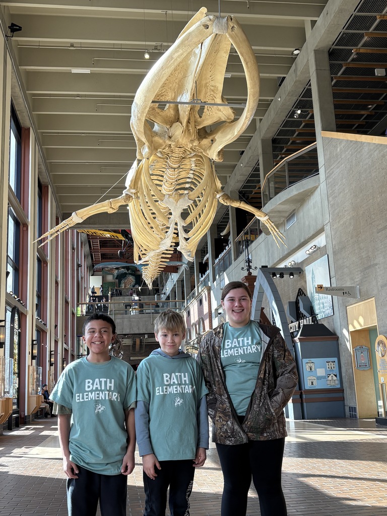 Boys standing under large skeleton