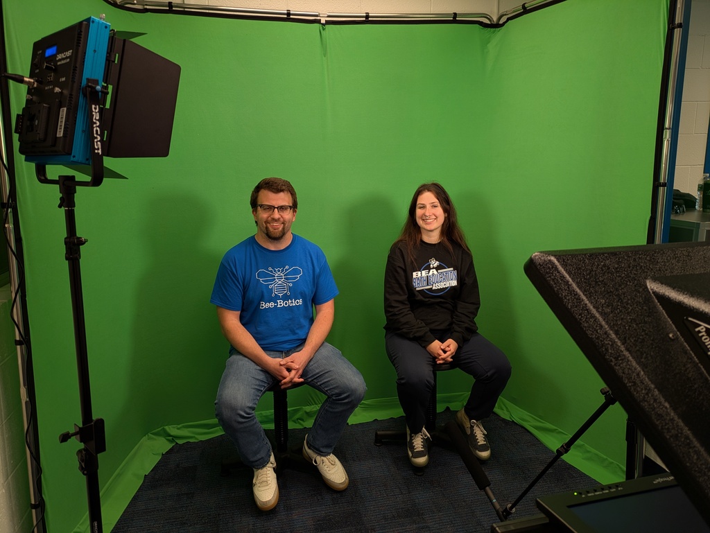 Ms. Helms and Mr. Curl sitting in front of the green screen