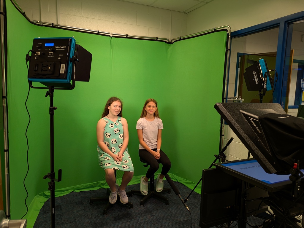 Girls sitting on stools in front of green screen