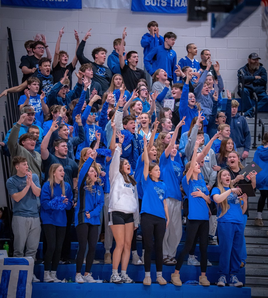 Students cheering in the stands at basketball game