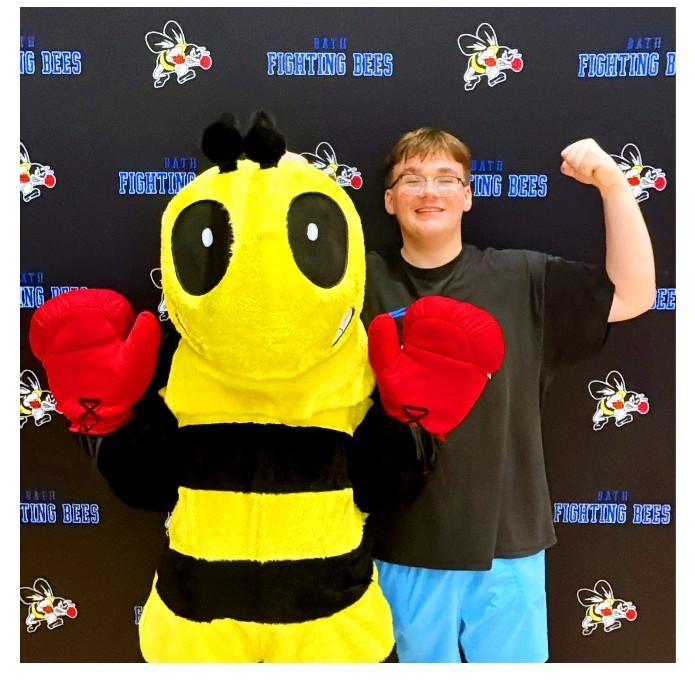 Boy standing next to bee mascot in photo booth