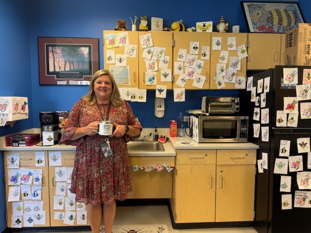 Principal standing in front of cupboards
