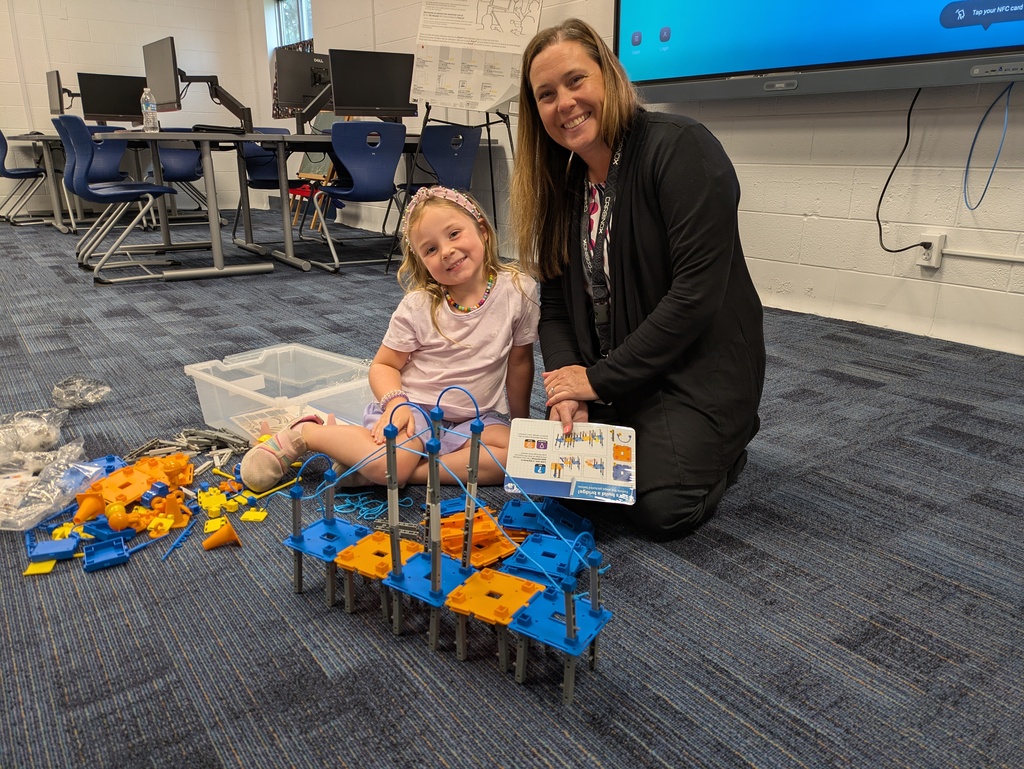 Student with Mrs. Grennell on the floor with a bridge project