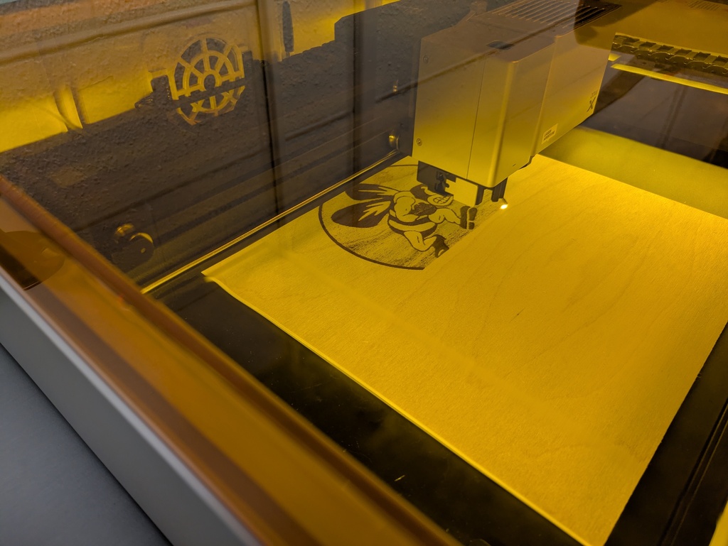 Laser cutter creating a Bath Bee Logo in wood