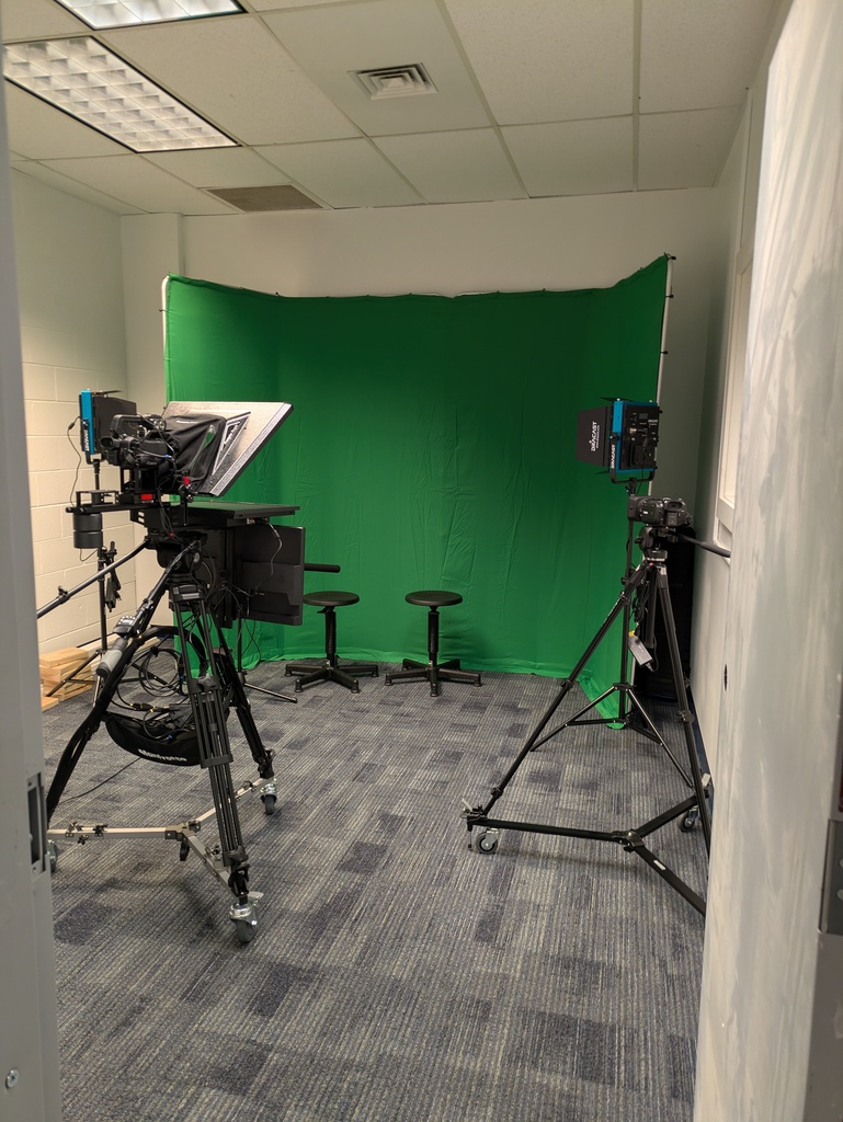 A studio room with cameras, teleprompter, and green screen.