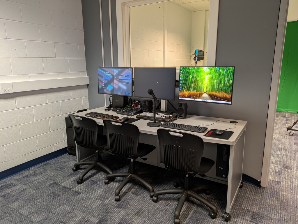 A studio control center with three monitors.