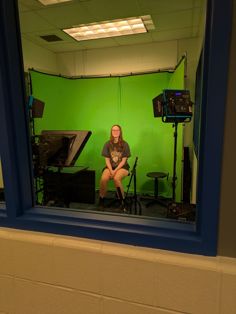 Student sitting on stool in front of green screen