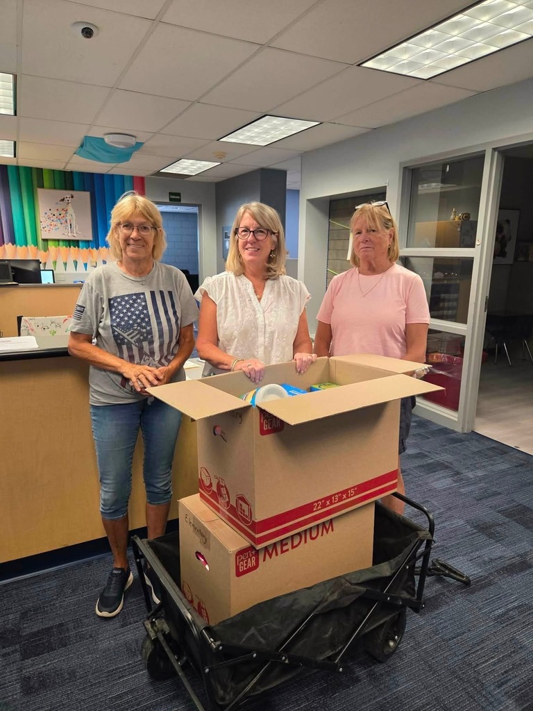 Mrs. Taylor and Auxiliary ladies standing next to boxes of school supplies
