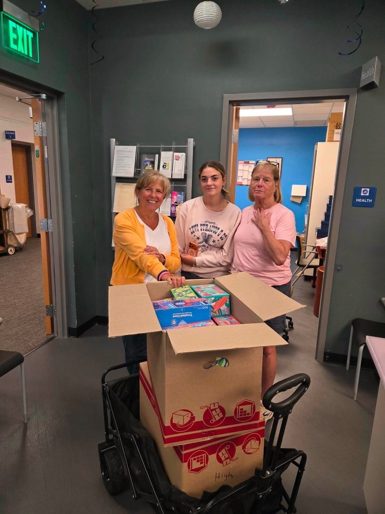 Mrs. Cook and Auxiliary ladies standing next to boxes of school supplies