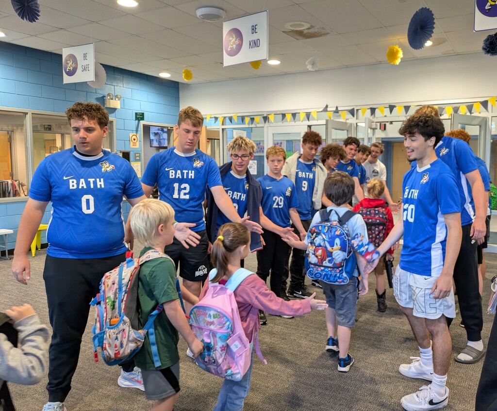 Students walking in the building shaking hands of players