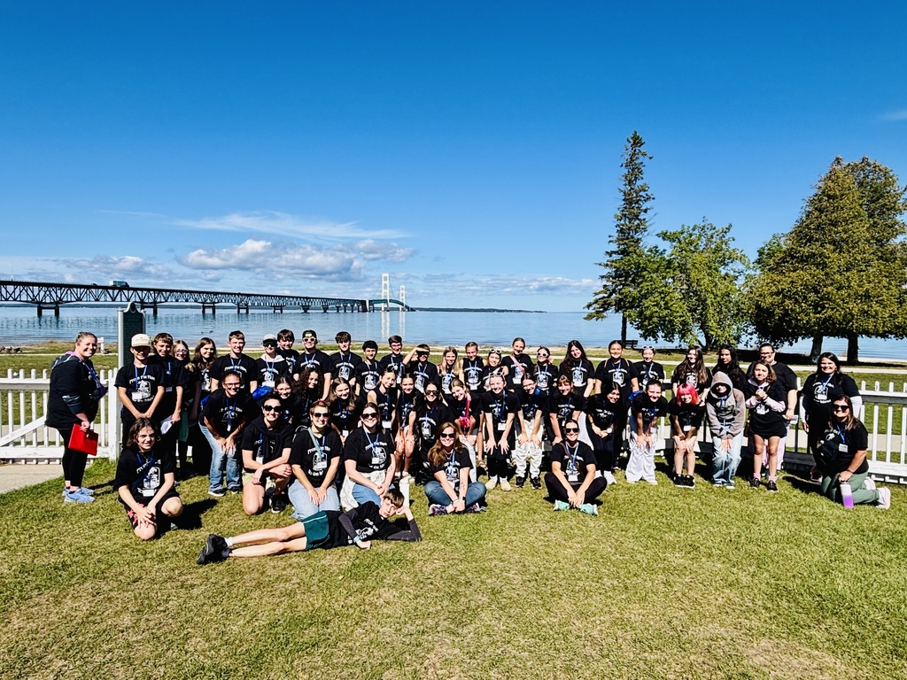 Students and chaperones posing for a photo in front of the Mackinac Bridge.
