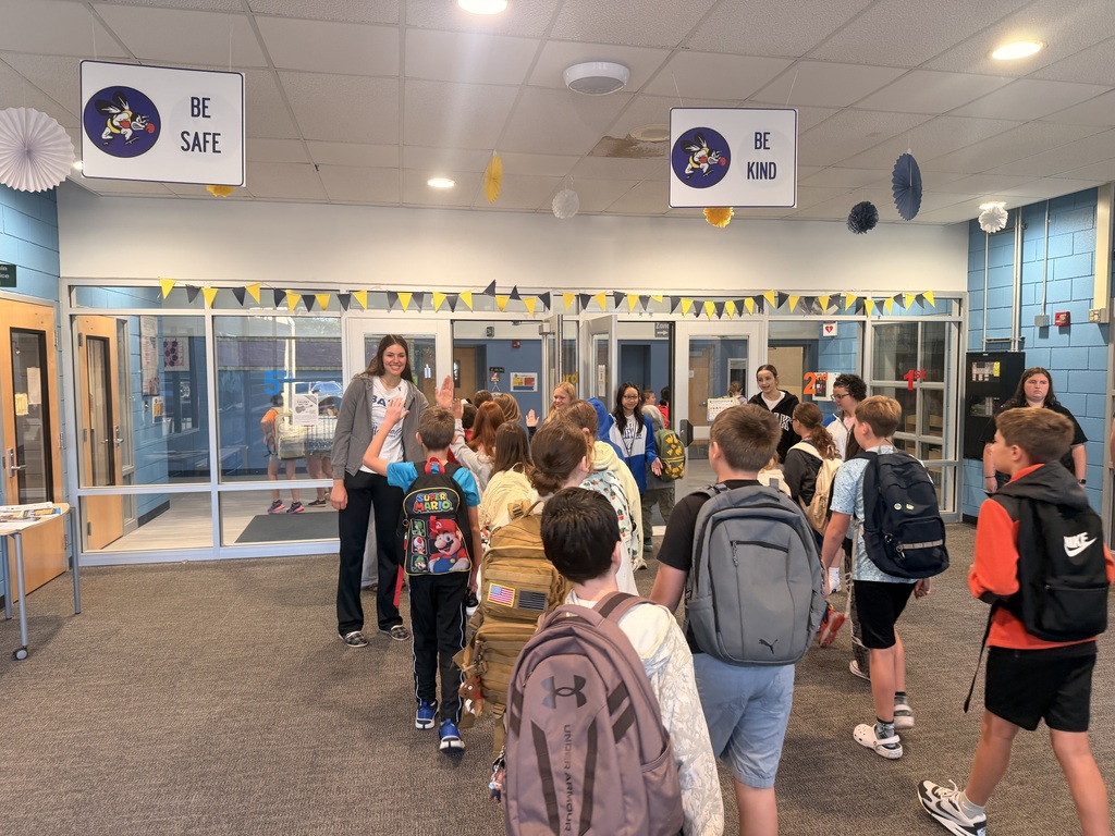 Students giving volleyball players a high five as they enter the building