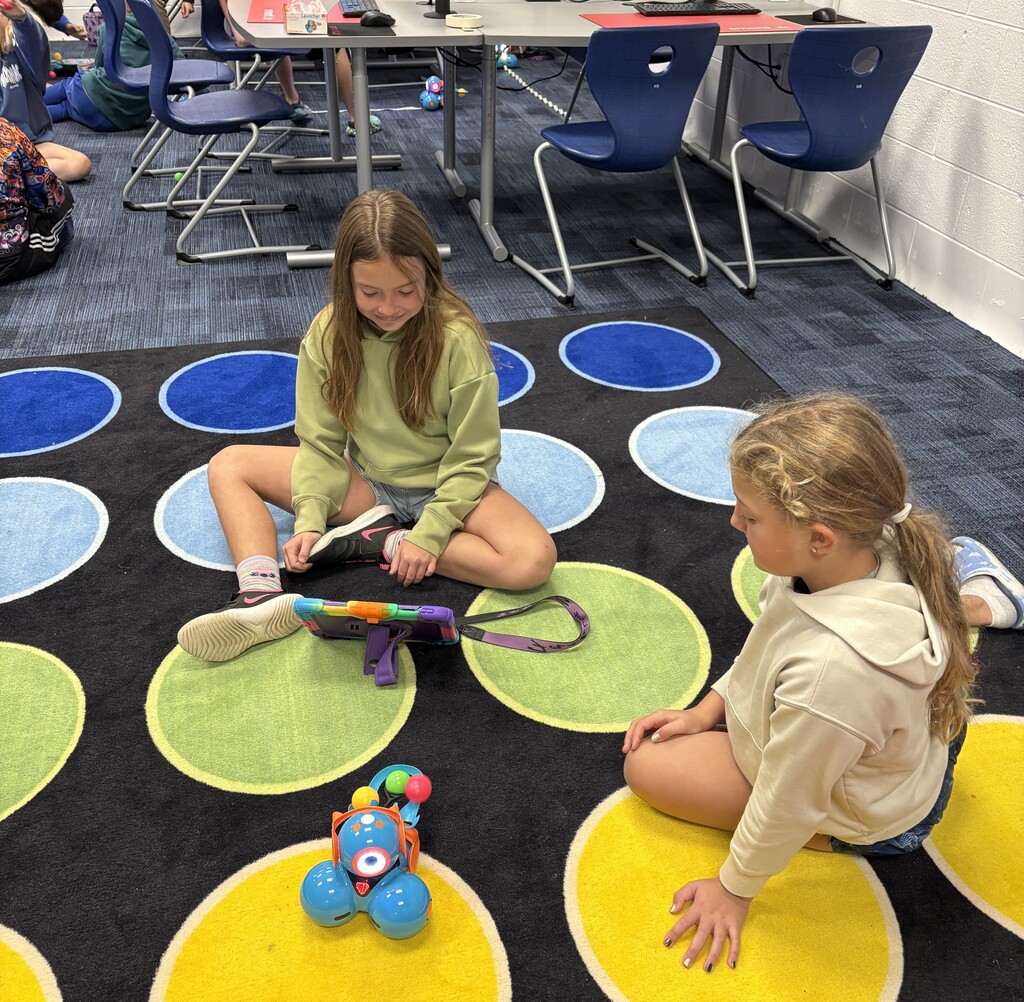 Girls sitting on floor with ipad and robot