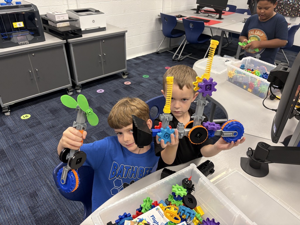 Boys holding projects they made with gears