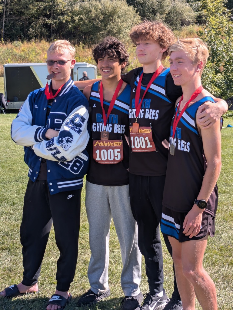 Four boys from the Bath Cross Country Team with their medals. One boy has his medal in his mouth.
