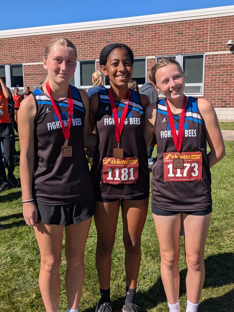 3 girls cross country runners standing together wearing medals with red ribbons around their necks