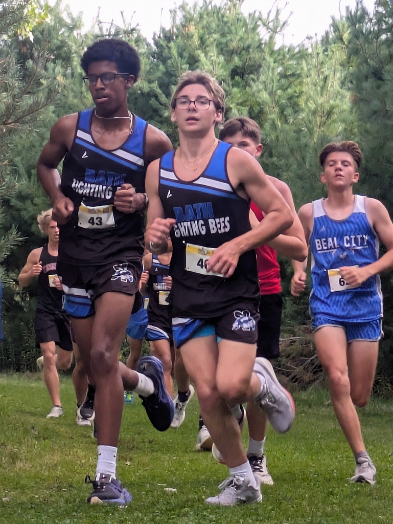 Group of students running on the grass led by two boys from Bath Cross Country Team