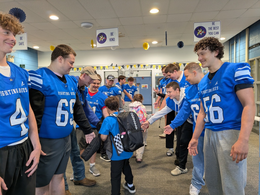Football players wearing with blue jerseys on greeting children as they walk in the lobby