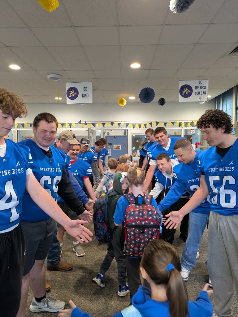 Football players wearing with blue jerseys on greeting children as they walk in the lobby