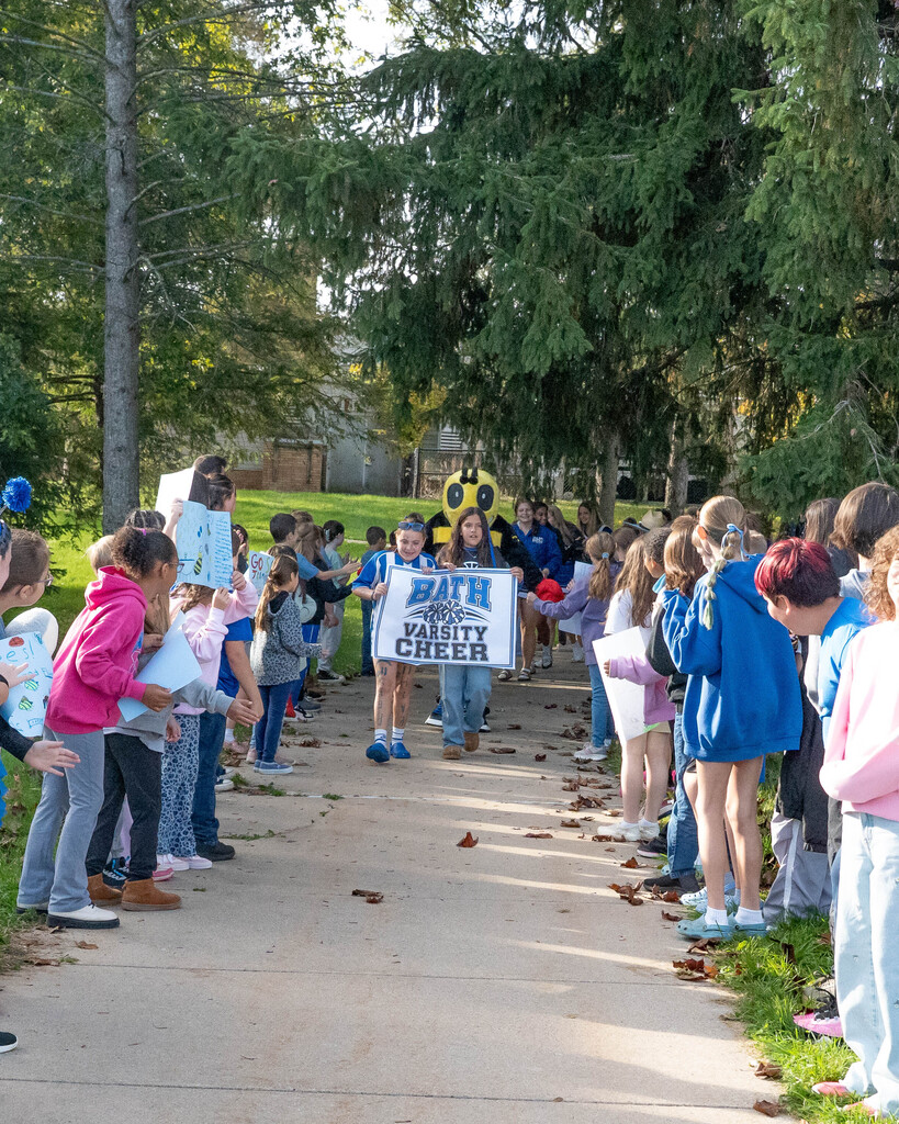 Elementary students lining the sidewalk holding sign to support high school athletic teams