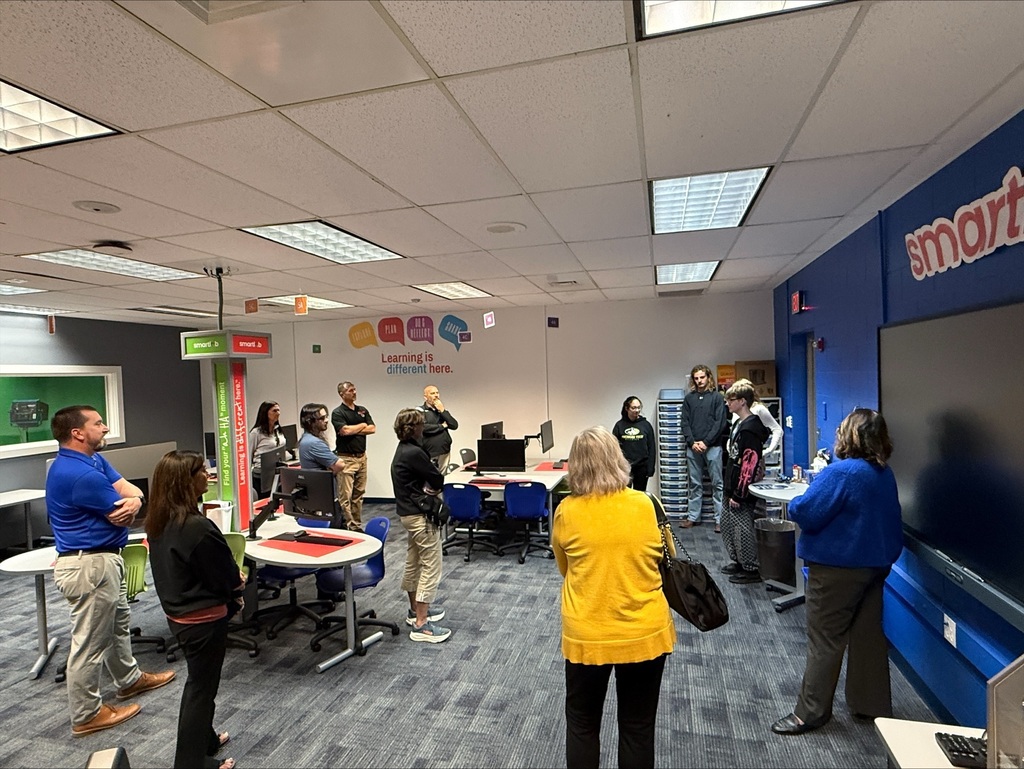 Staff and guests standing high school SmartLab listening to students speaking