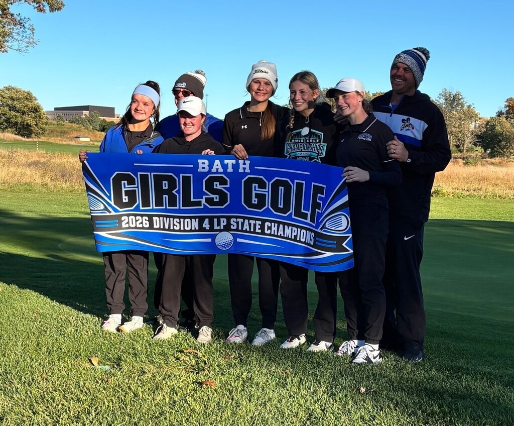 The girls golf and coaches team holding a state championship banner