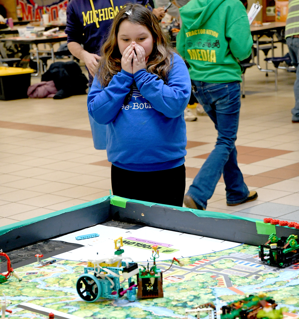 Girl with Bee Botics shirt on watching robot on table