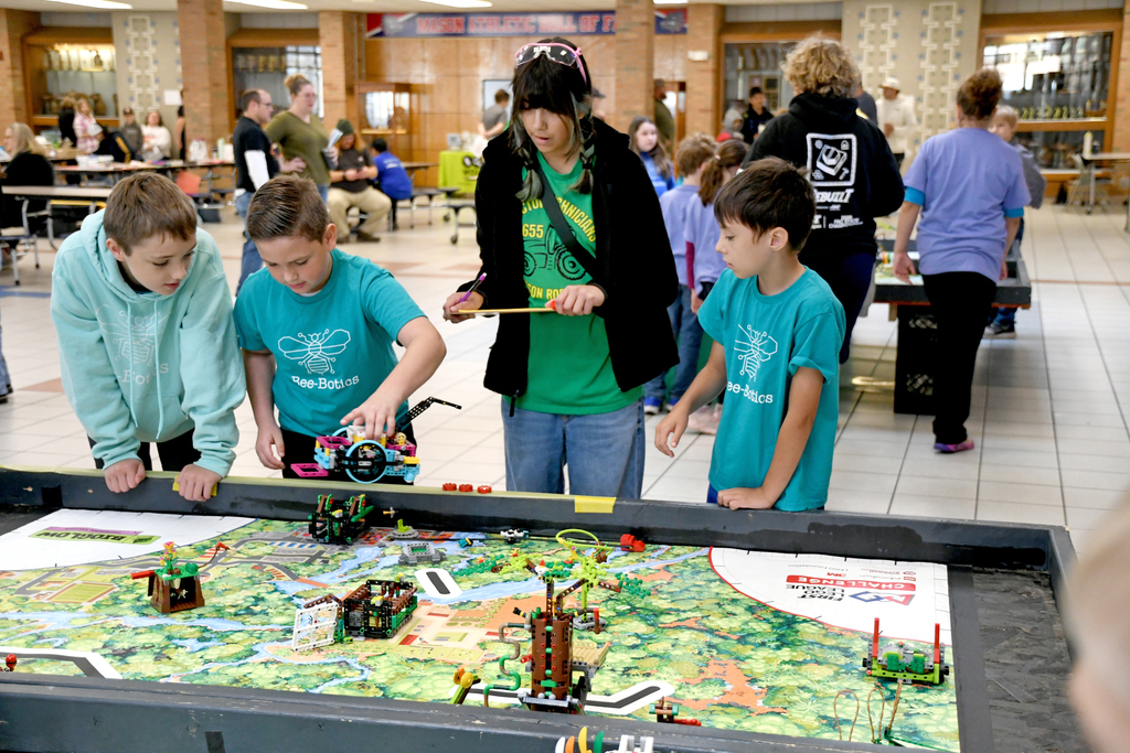 3 boys with Bee Botics shirts on being judged in a competition