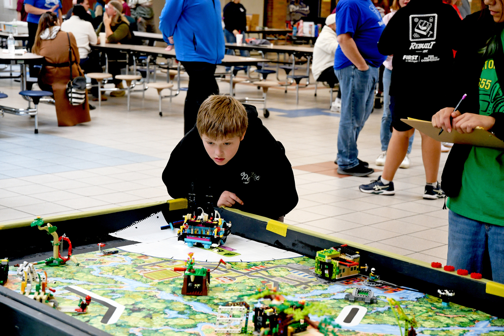 Boy leaning over table watching his robot