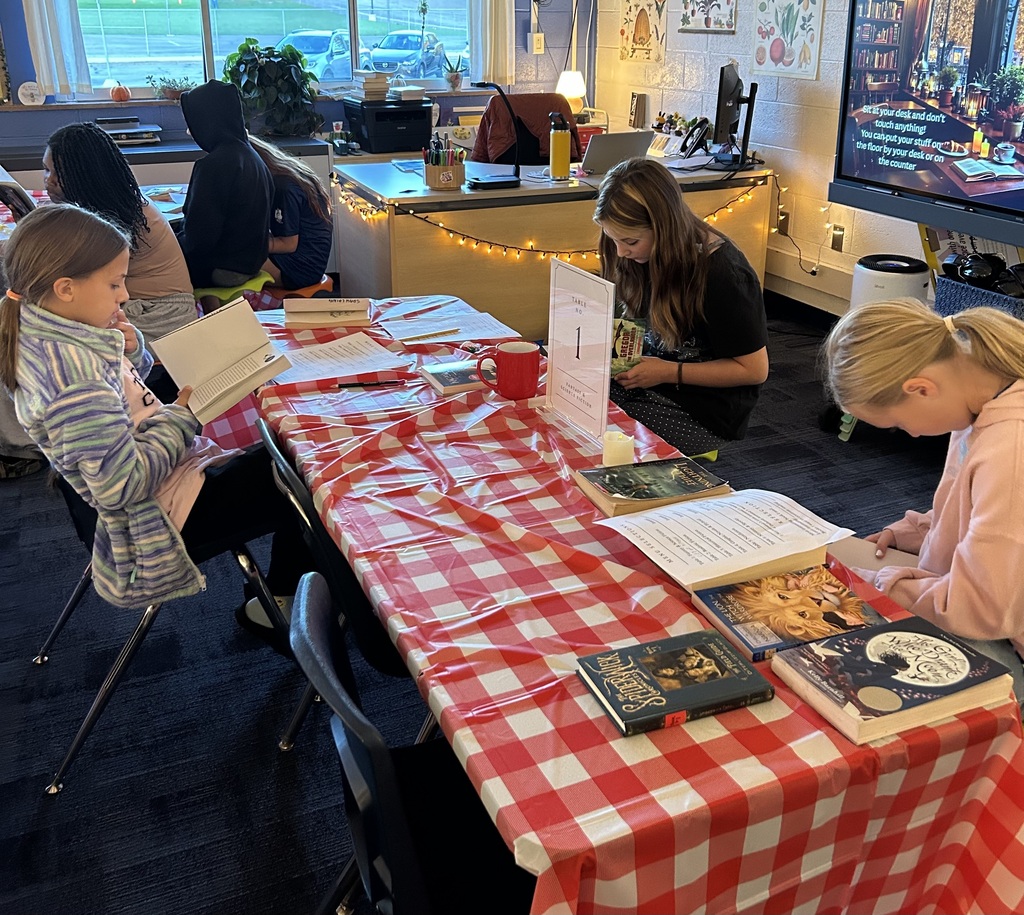 Students sitting at table with red and white checkered table cloth reading books