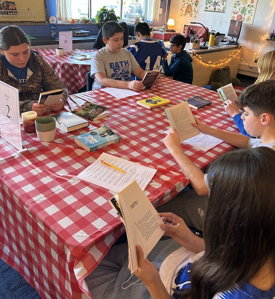 Students sitting at table with red and white checkered tablecloth reading books